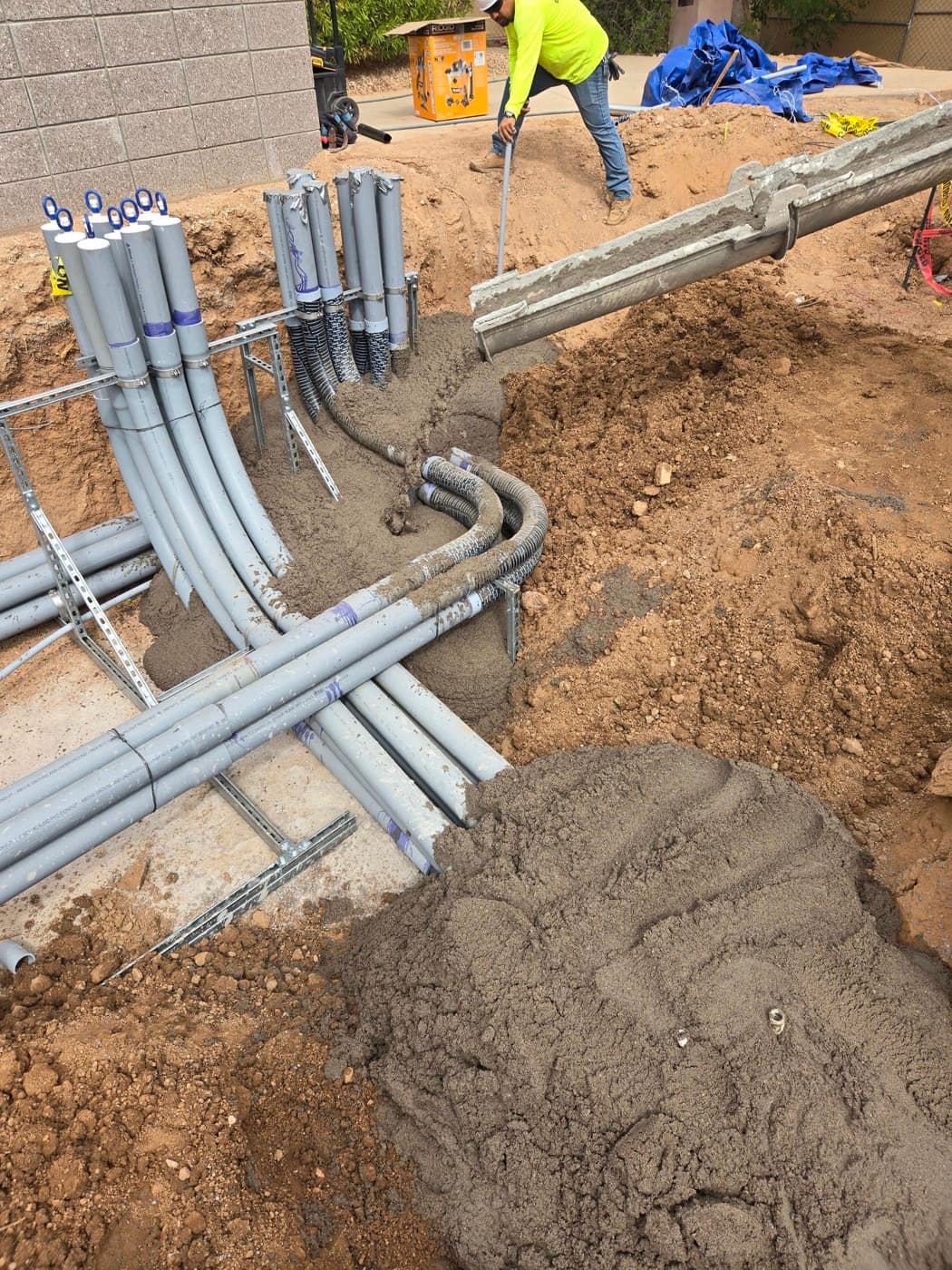 Slurry backfill being poured around racked conduit