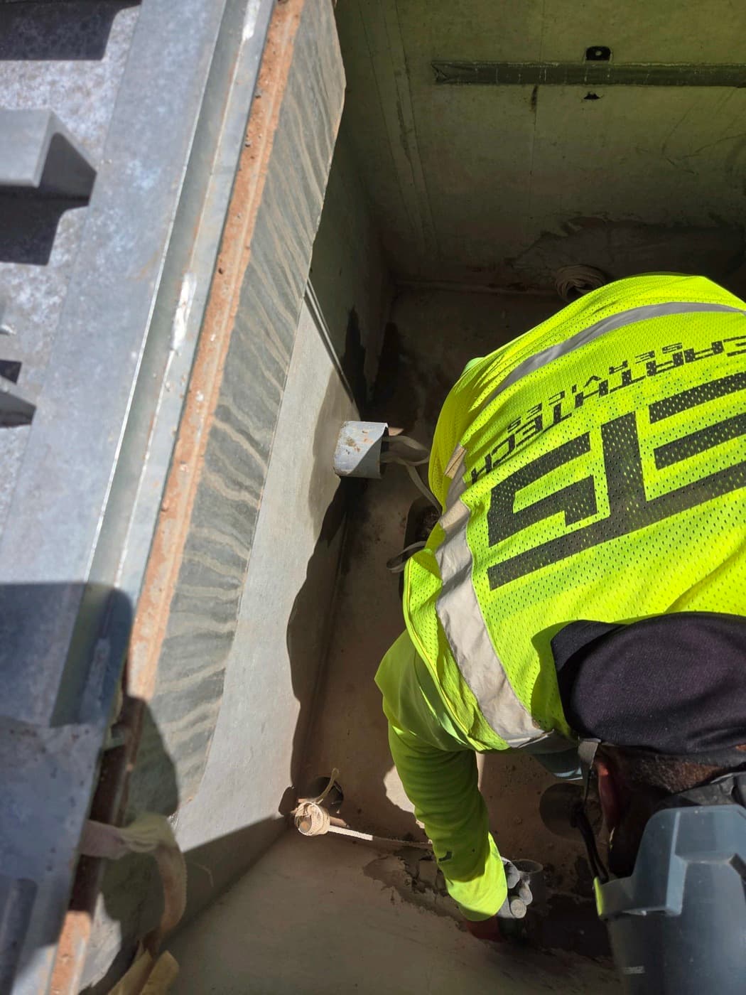 EarthTech crew member in an ETS vest working inside a utility vault