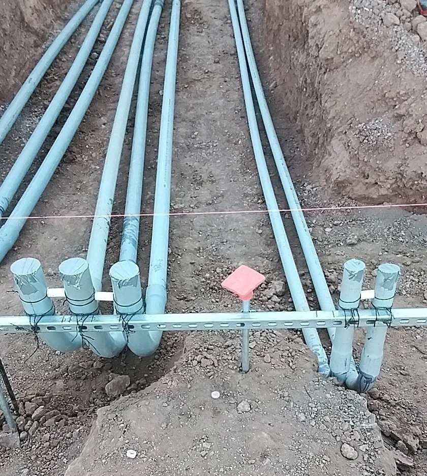 Conduit sweeps capped and racked on strut, beside a survey stake